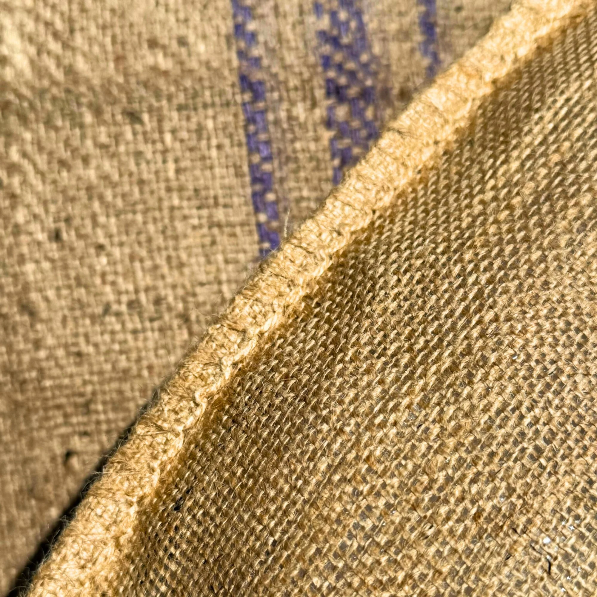 Close-up of textured fabric, with a visible seam and a pattern of blue stitches.