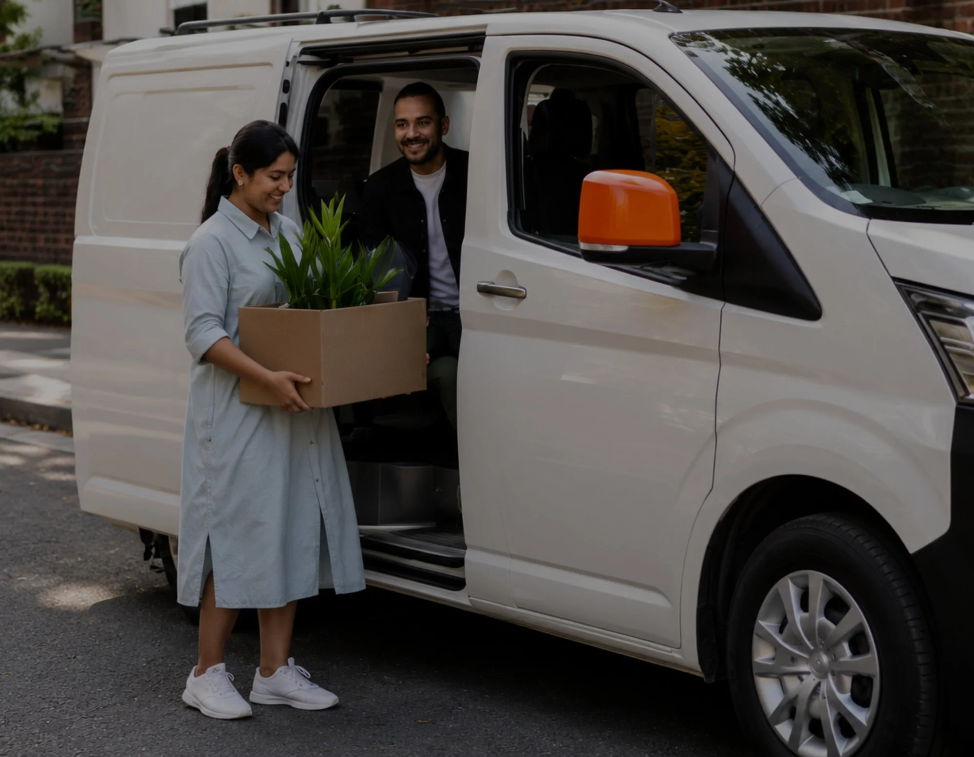 A couple holding a cardboard box, using a carshare car at Home+ McGraths Hill.
