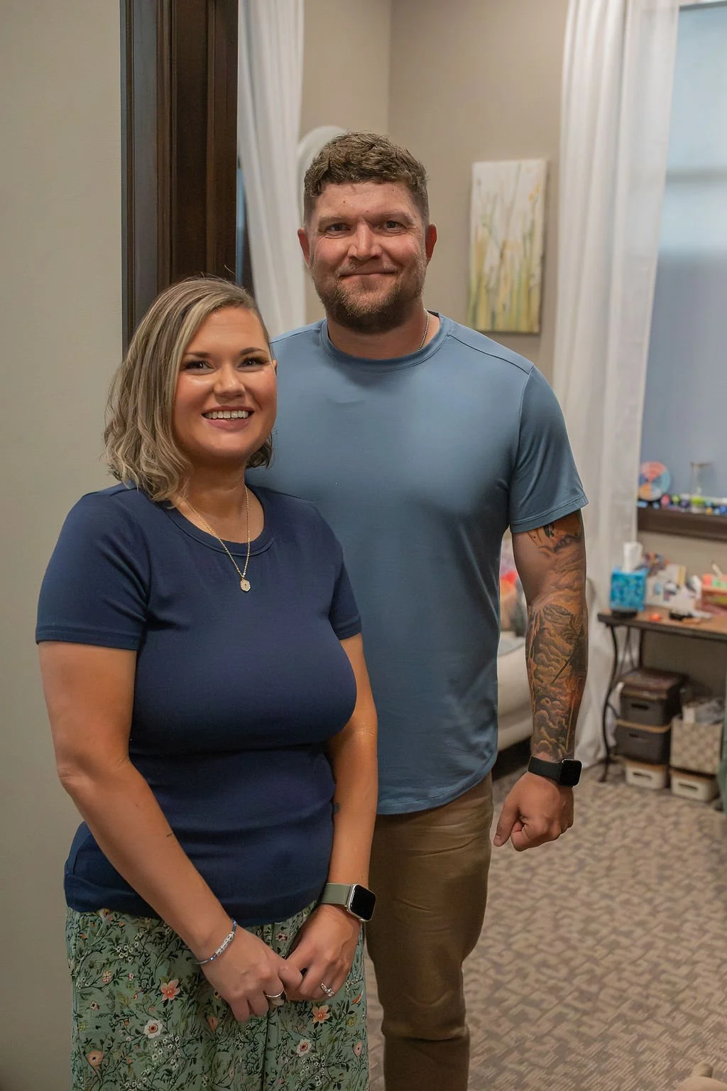 Krysta Winter, Christian counselor, and Kyle Winter, Christian men’s mental health coach in Sioux Falls, SD, standing together and smiling in their counseling office.