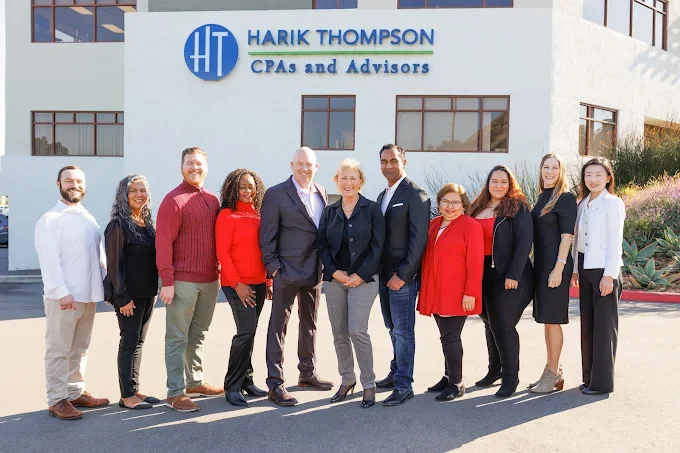 Group of ten professionally dressed people standing in front of the Harik Thompson CPAs and Advisors office building.