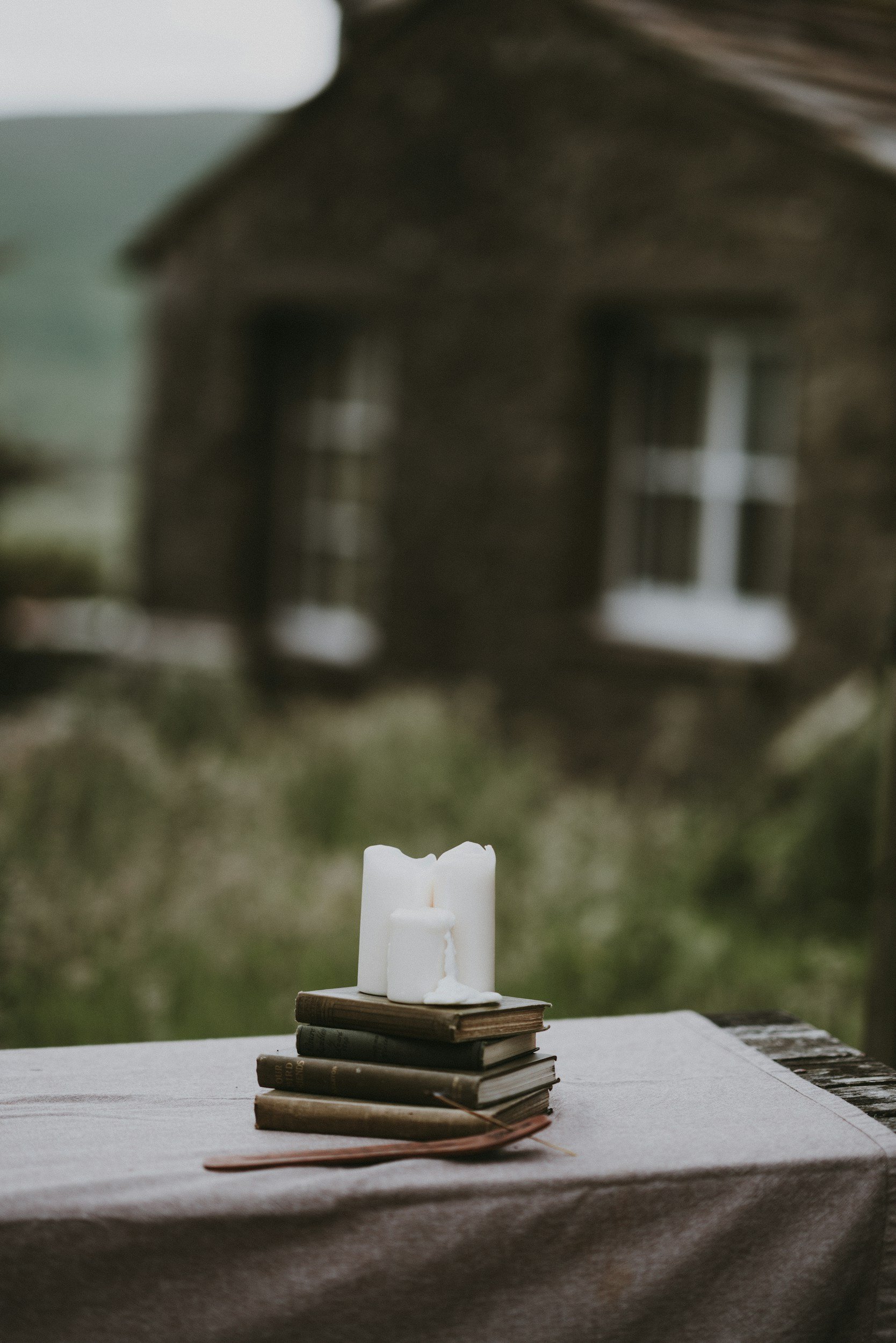 Books and candles on an outdoor table in a quiet, welcoming setting.