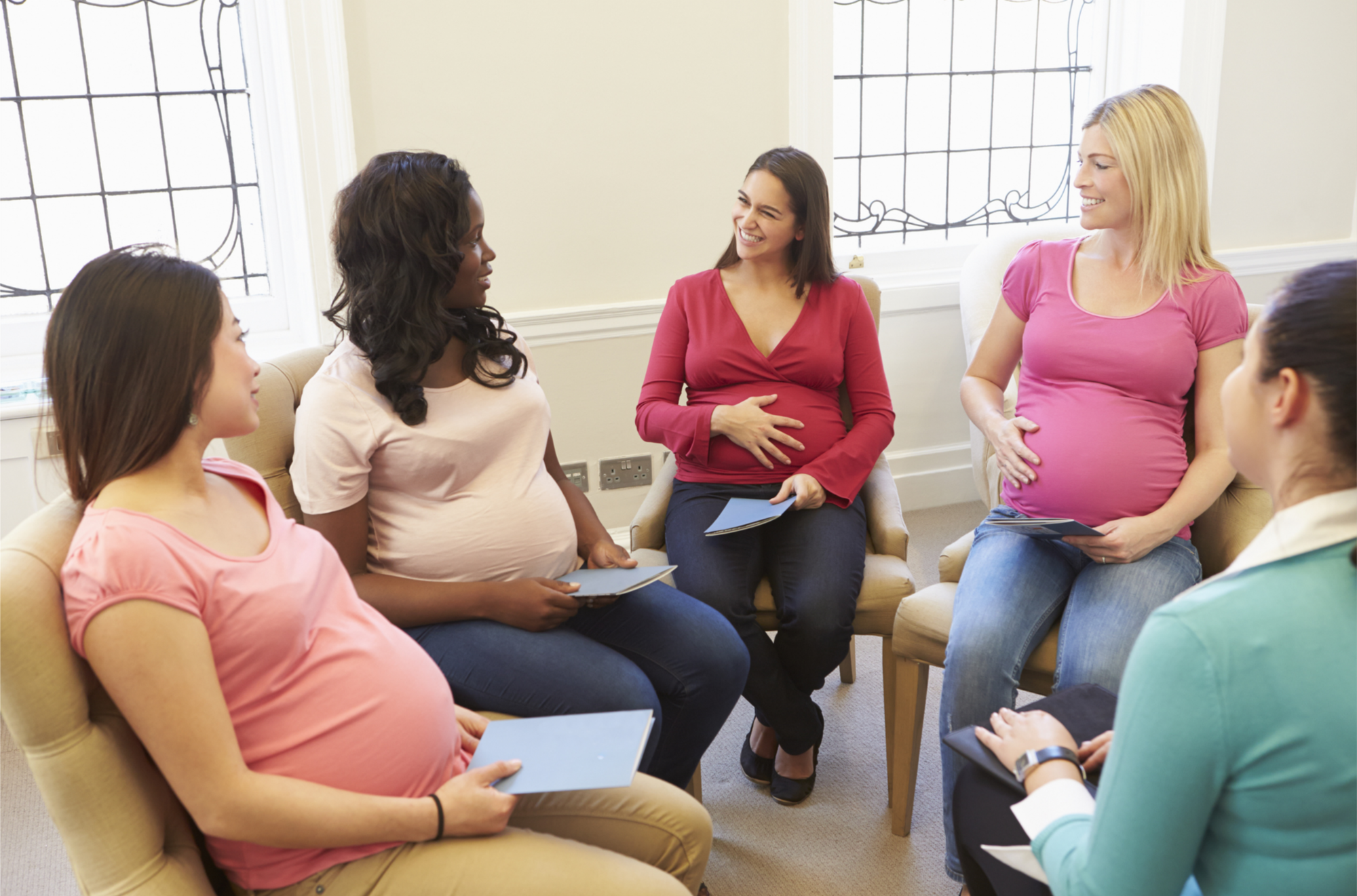 Pregnant people sitting together in a circle during a childbirth education class.