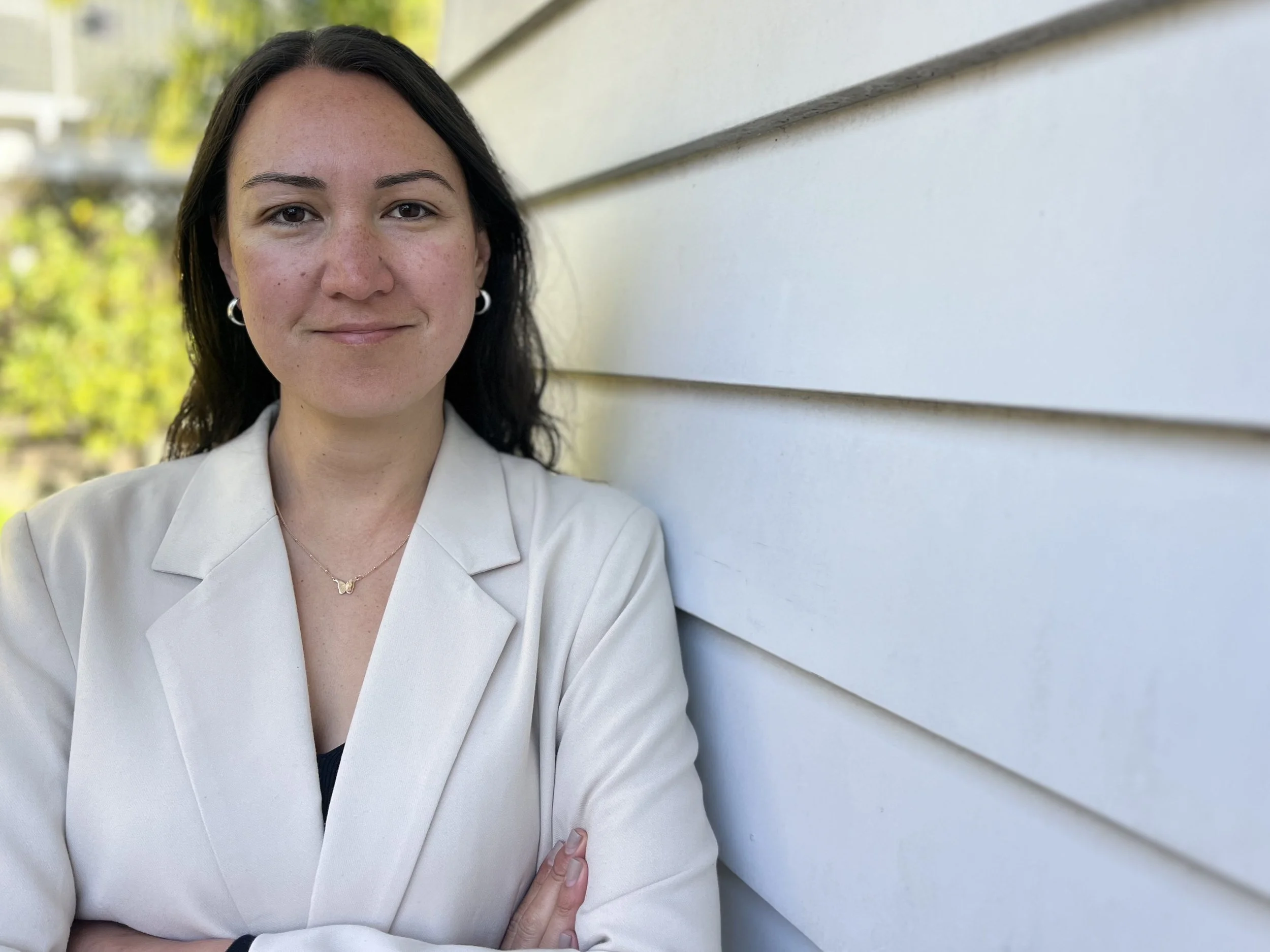 Melanie Tuala, senior communications consultant, smiling outdoors in a blazer.