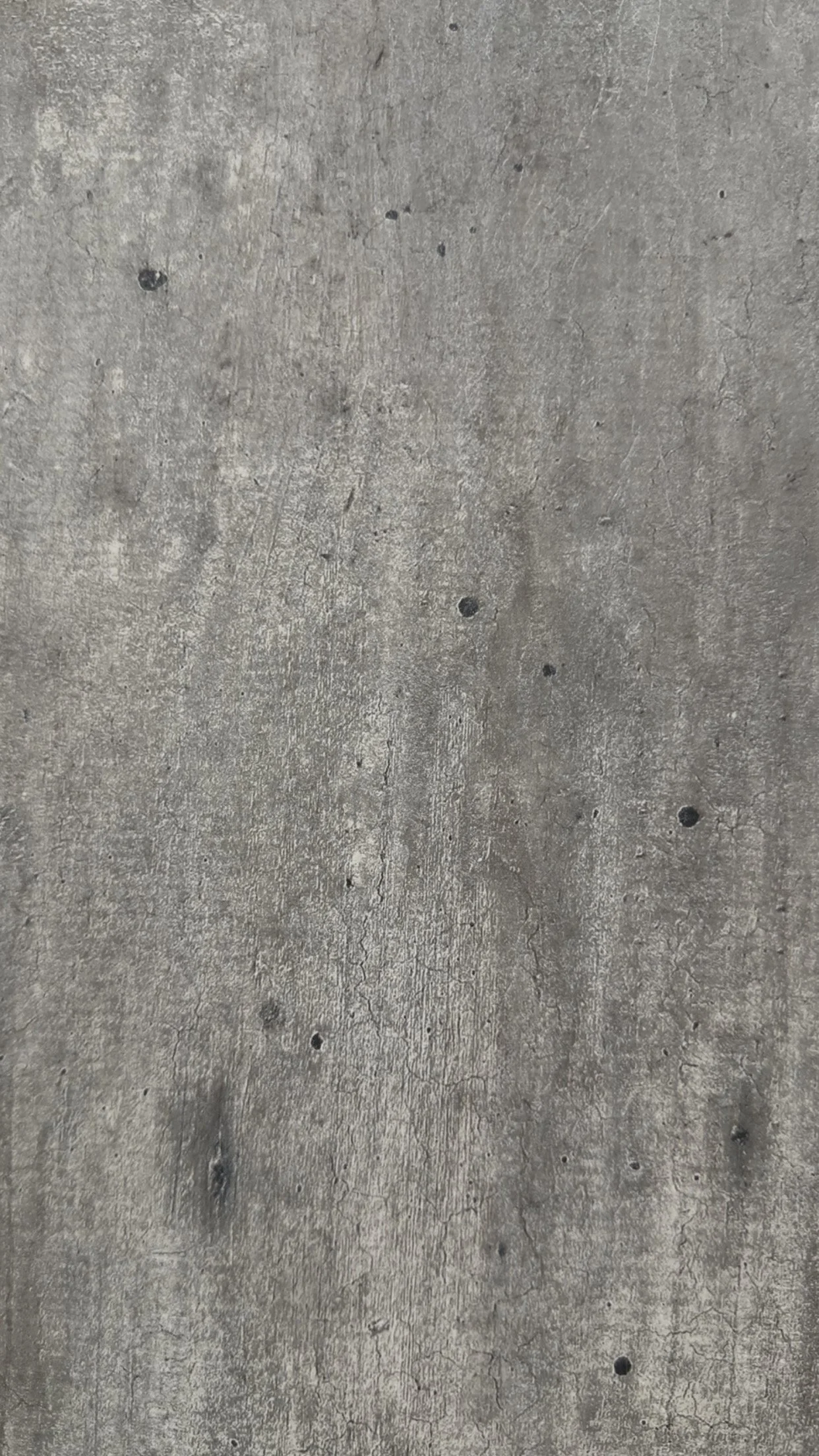 A close-up view of a gray concrete floor with small black and white speckles and some cracks.