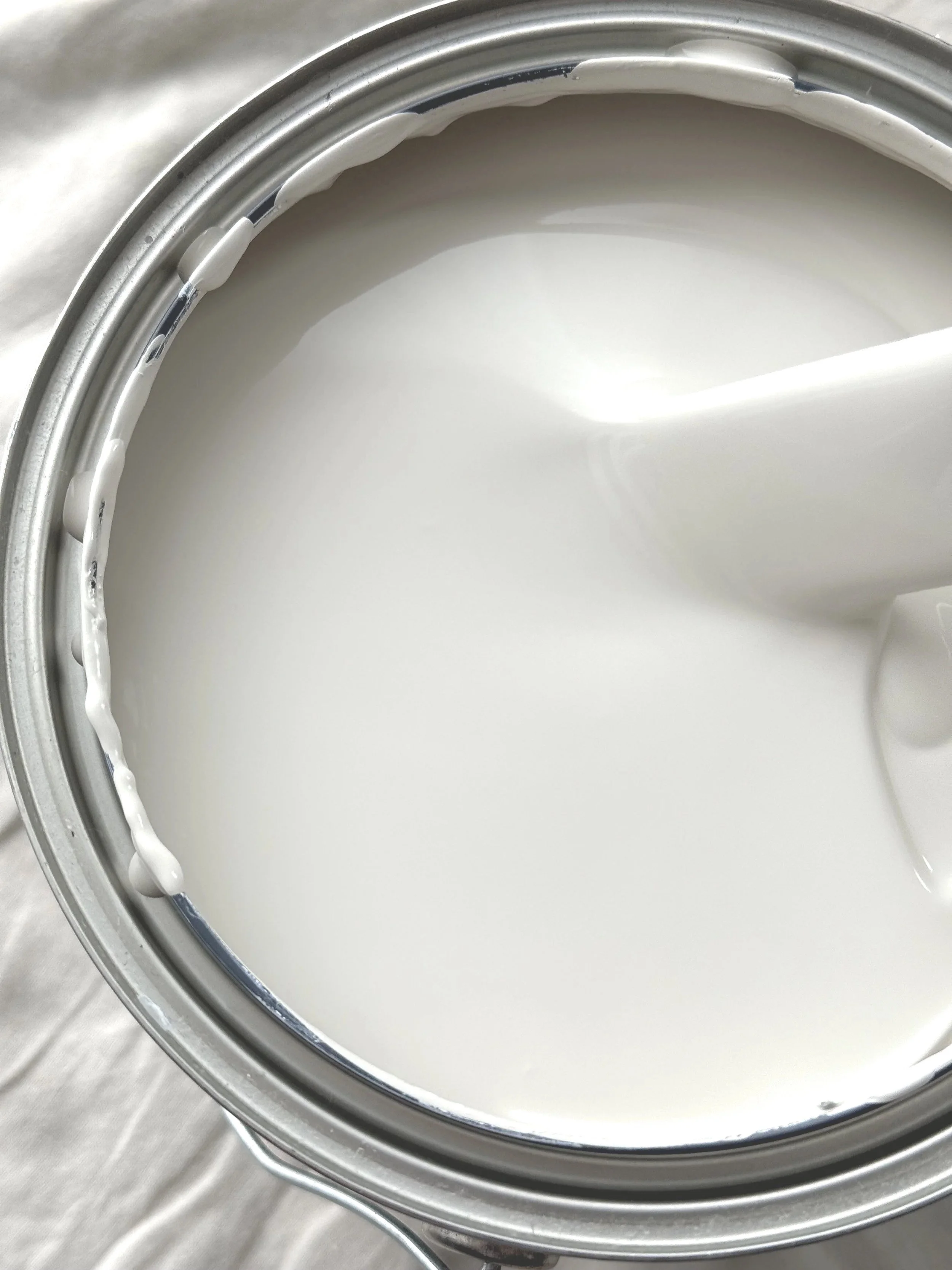 A paint with the lid removed, showing the white creamy paint inside.