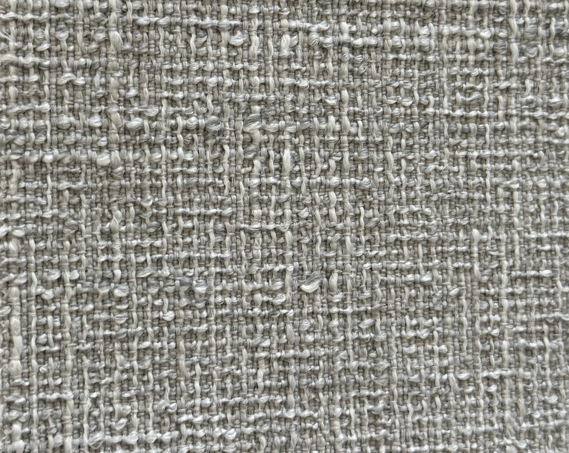 Close-up of a textured beige woven fabric or carpet with a pattern of interlaced threads.