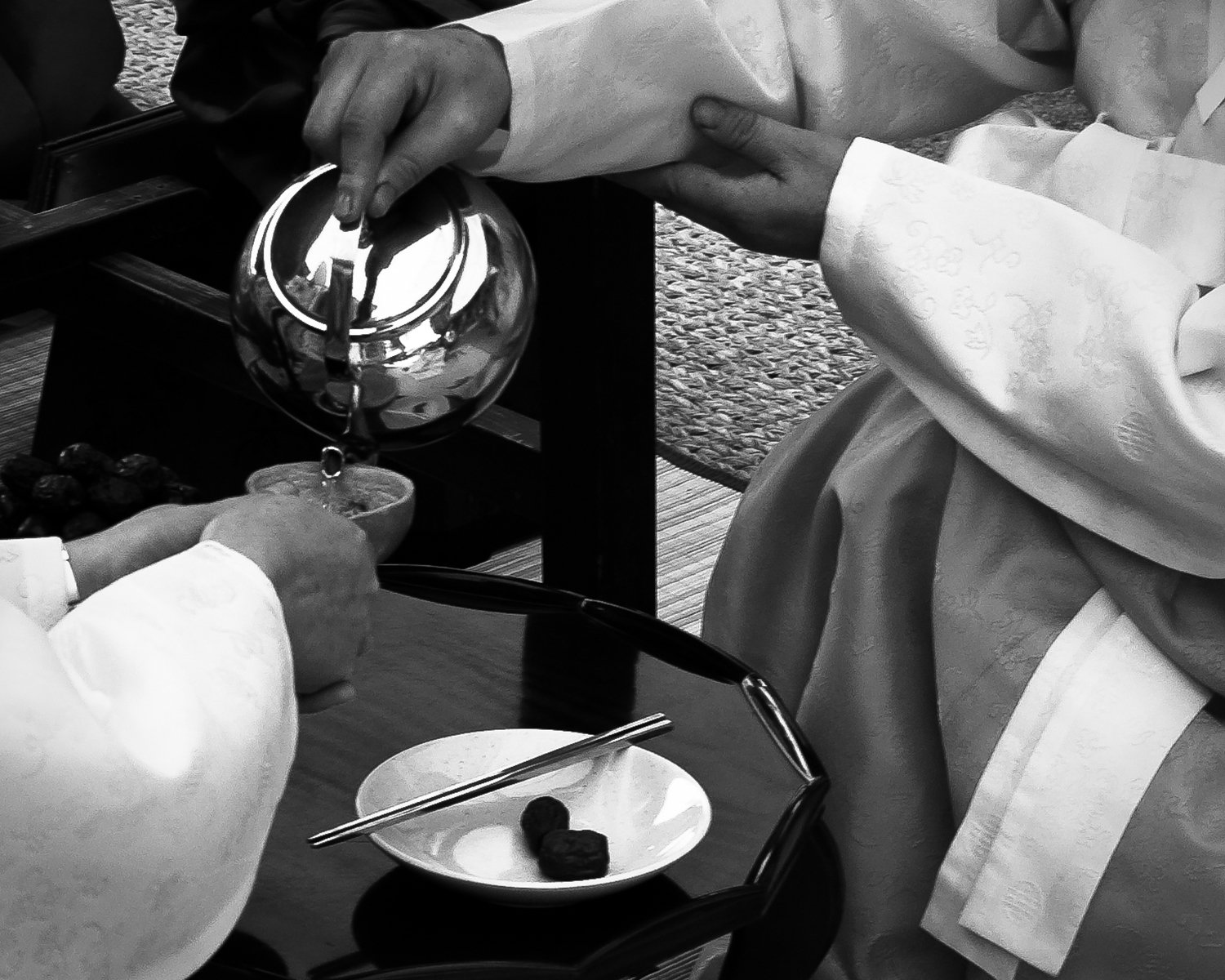 People pouring tea into small cups during a traditional tea ceremony.