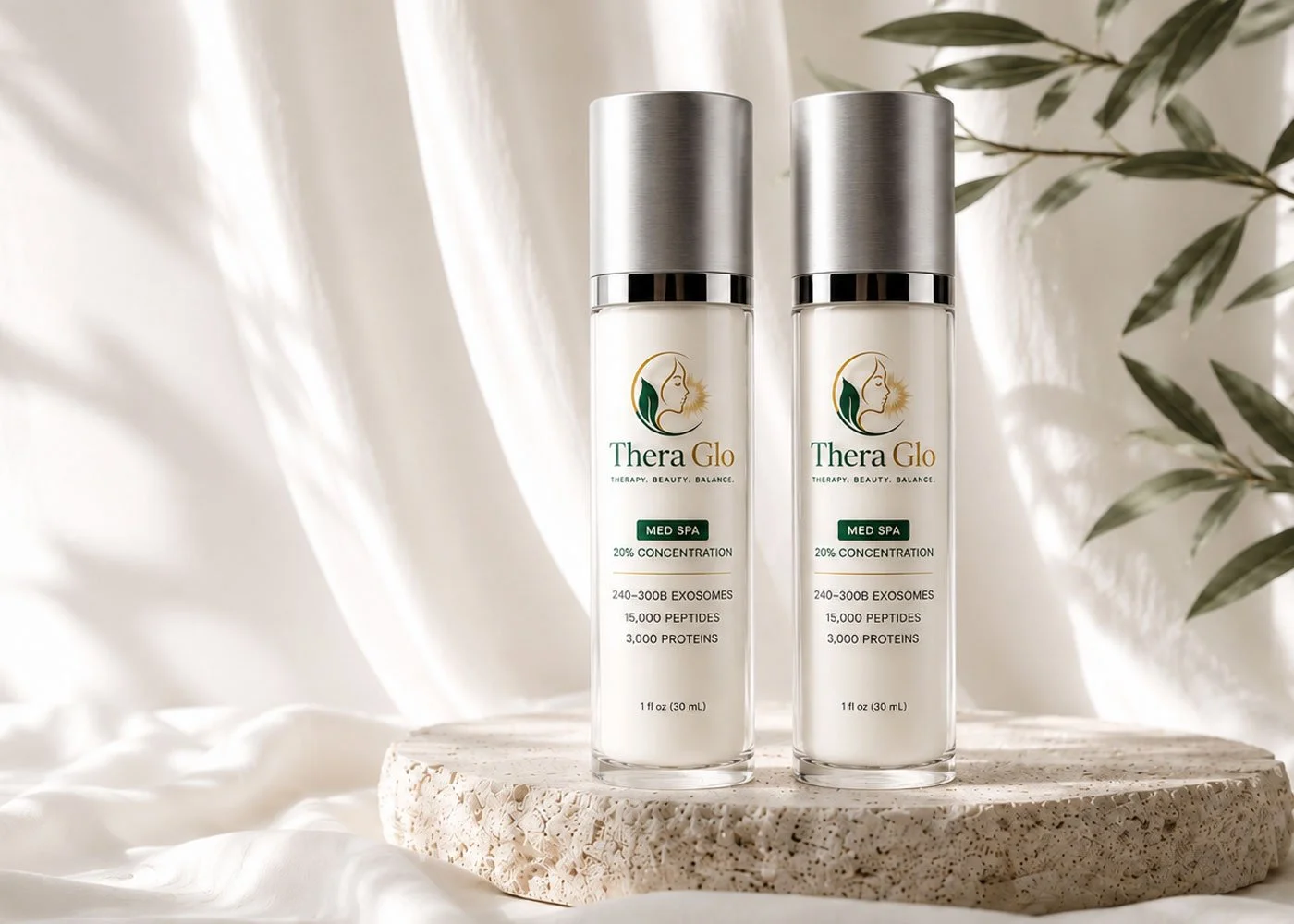 Two bottles of TheraGlo skincare product with silver caps on a round, textured stone surface, with soft white curtains and green foliage in the background.