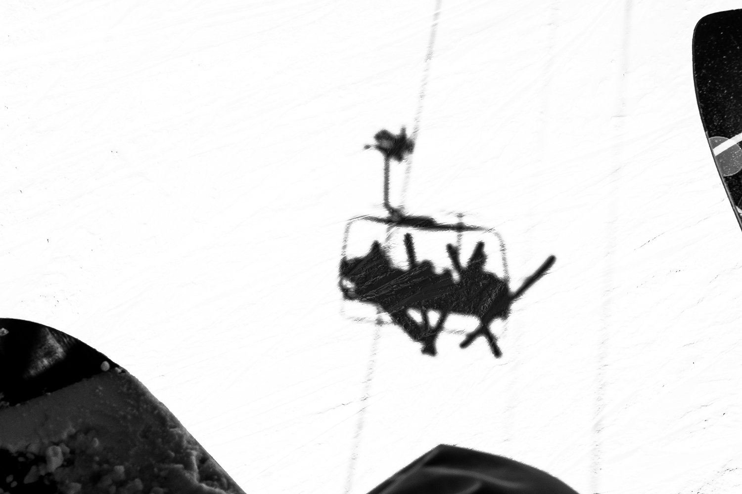 Shadow of a person riding a snowmobile on snow, taken from above.