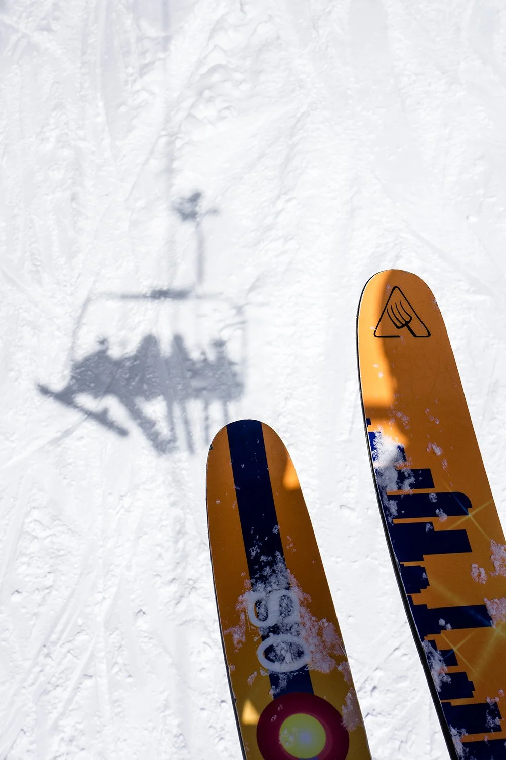 Ski poles and skis on snow with shadow of ski lift.