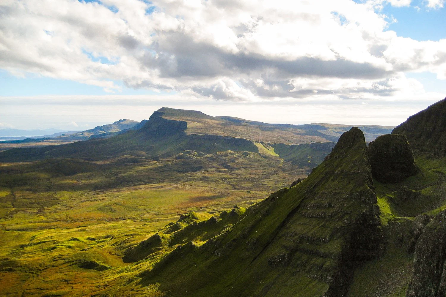 A landscape of green moss-covered mountains and valleys with a cloudy sky.