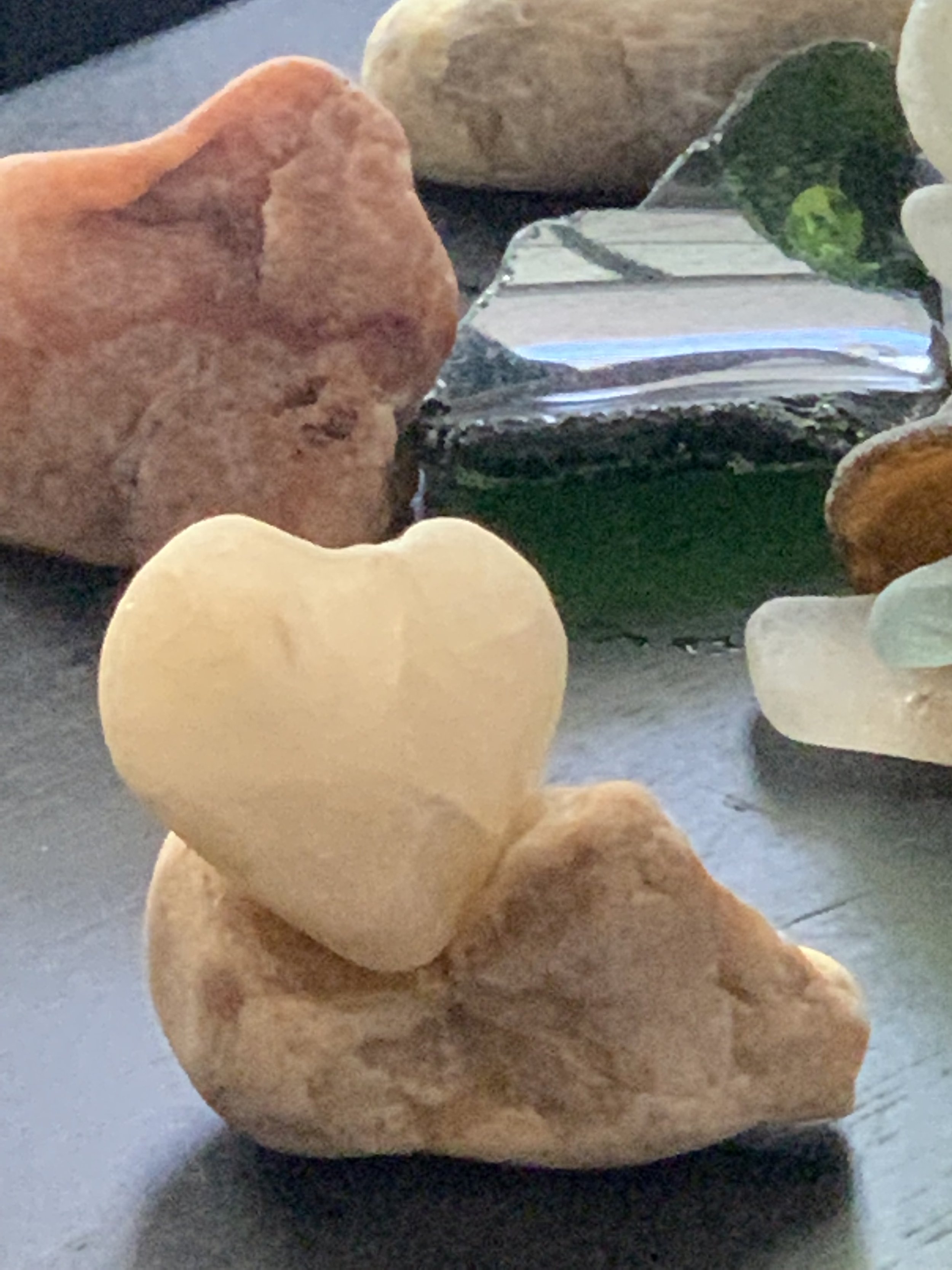A collection of colorful rocks on a surface, with a transparent glass item to the right.
