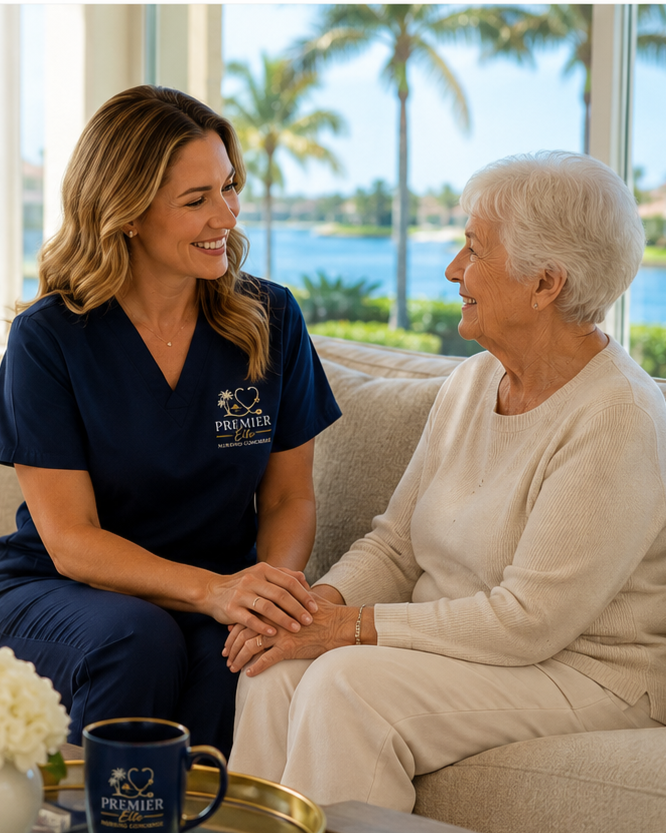 A caregiver and an elderly woman sitting on a sofa, holding hands and smiling at each other, in a bright room with large windows and a view of palm trees and water outside.