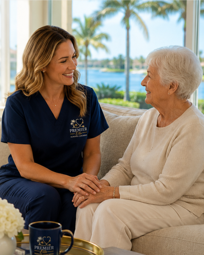 A caregiver and elderly woman smiling and holding hands inside a bright, scenic living room with large windows and a view of palm trees and water.