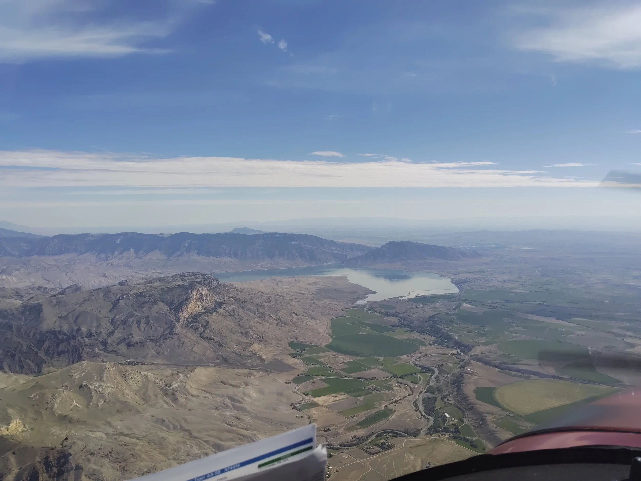 Aerial view of mountains, valleys, and lakes under a partly cloudy blue sky.
