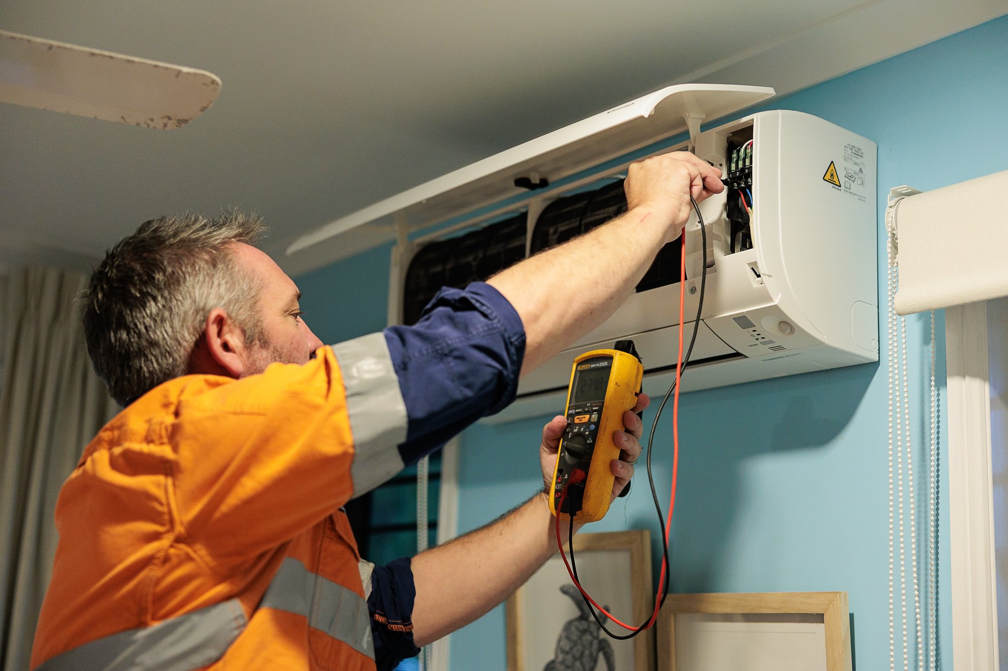 Air conditioning technician inspecting a split system in a Mackay home