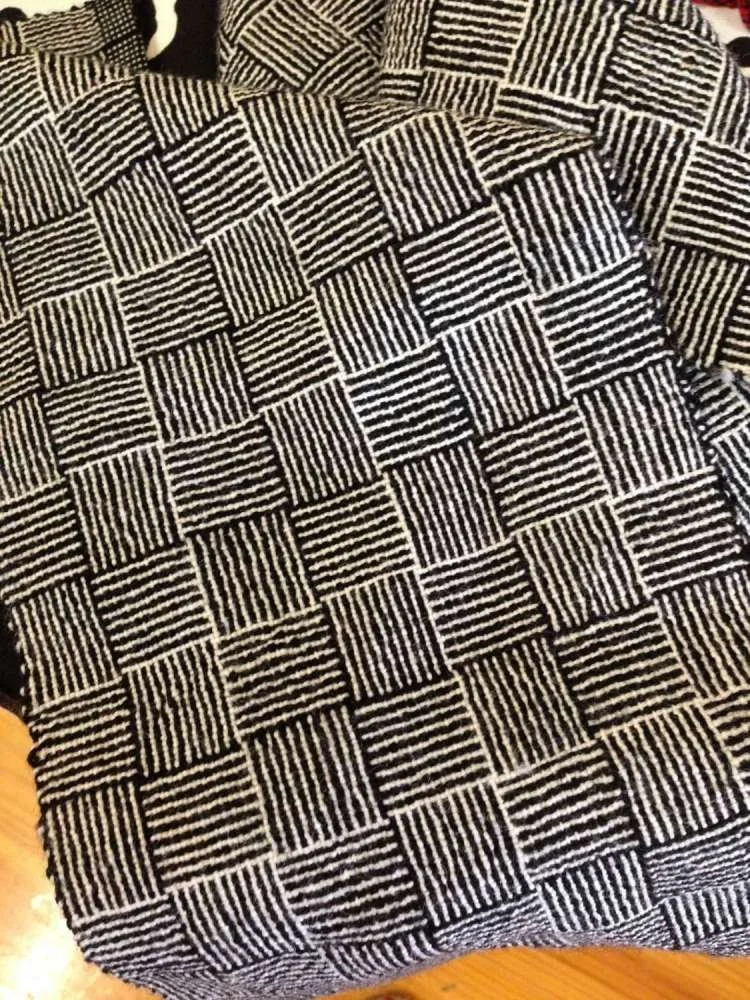 Close-up of a black and white checkered fabric with striped pattern in each square.
