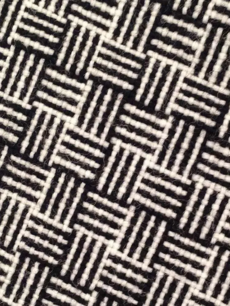 Black and white woven textile with a geometric pattern of squares and stripes.
