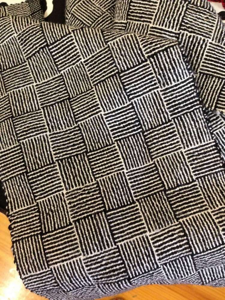 Close-up of a black and white checkered patterned fabric, likely a textile or blanket, with a horizontal striped design within each square.