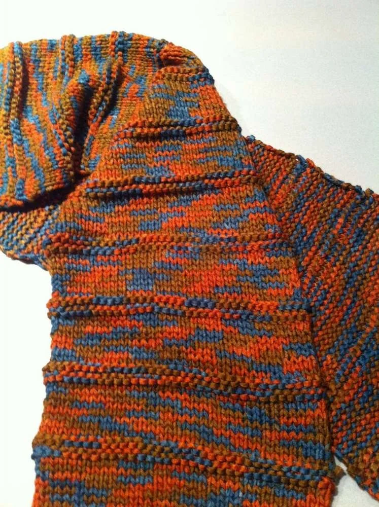 Close-up of a multicolored knitted sweater in orange, blue, and brown tones.