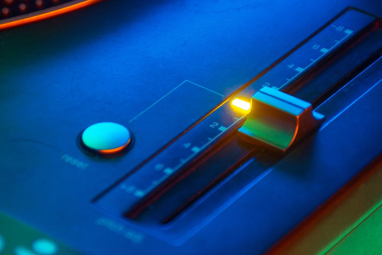 Control de pitch de tocadiscos technics de un equipo de DJ con luces azules y verdes.