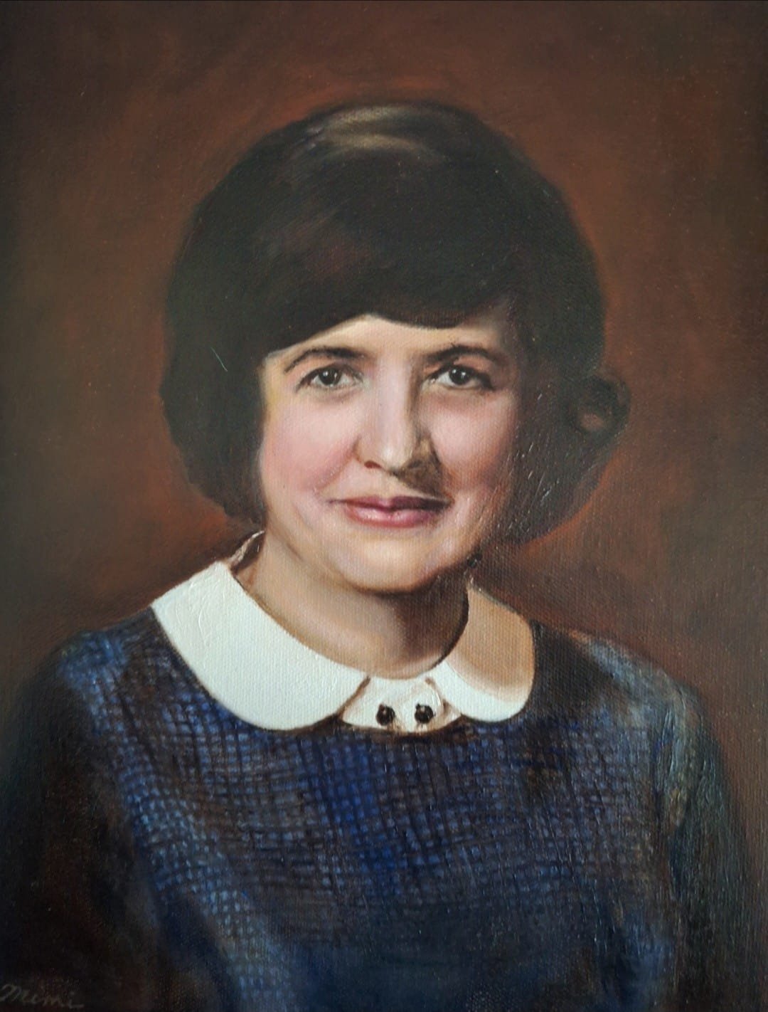 A portrait of a woman with short dark hair, wearing a dark blue textured dress with a white rounded collar and a decorative clasp at the neckline, against a brown background.