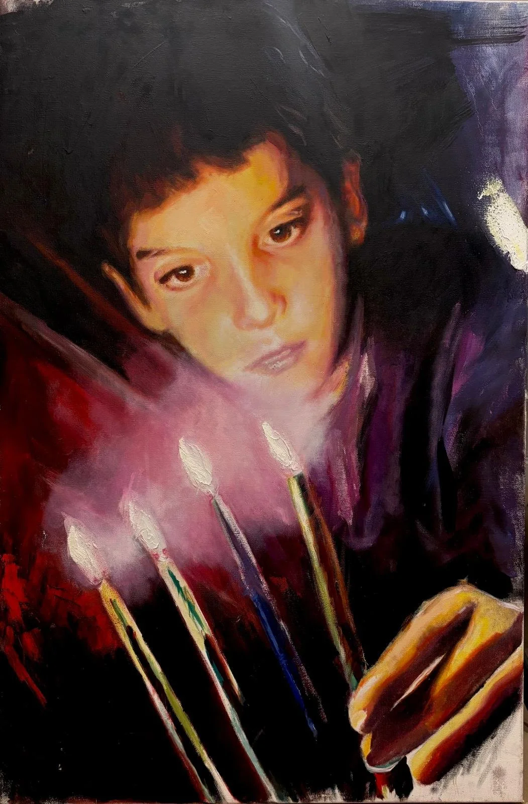 A portrait of a young person with short dark hair, looking directly at the viewer, surrounded by smudges of dark colors with some bright accents, with five burning candles in front of them and a partially visible smartphone in the lower right corner.