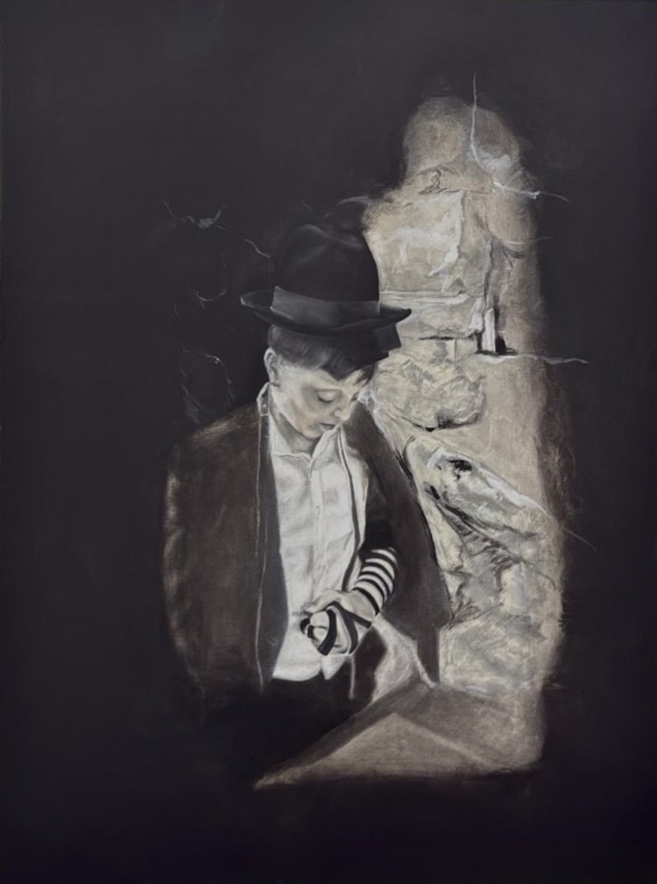 A young person wearing a black hat, white shirt, striped arm warmers, and a jacket, looking down at an object in front of them. The background is dark, with a mural of a fish, a castle, and a cityscape painted on a wall.
