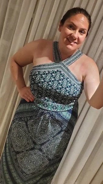 Woman taking a mirror selfie in a sleeveless patterned dress.