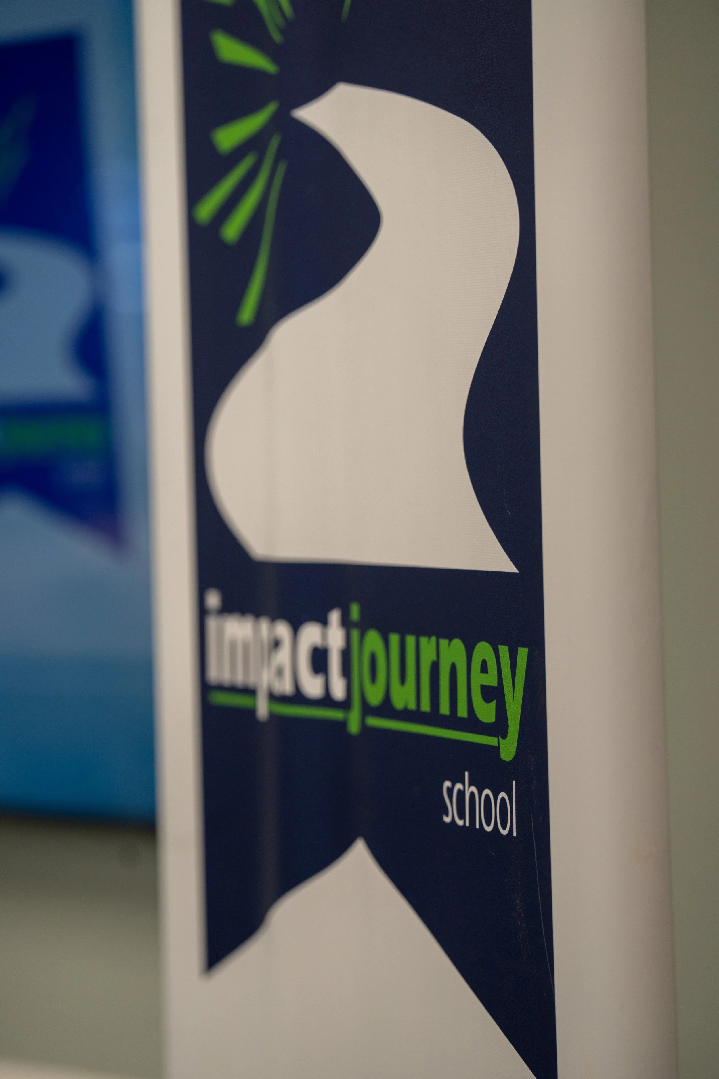 A sign with a silhouette of a person's head and a hand pressing against the side of the head. The sign has the words 'impact journey' with 'impact' in white and 'journey' in green.
