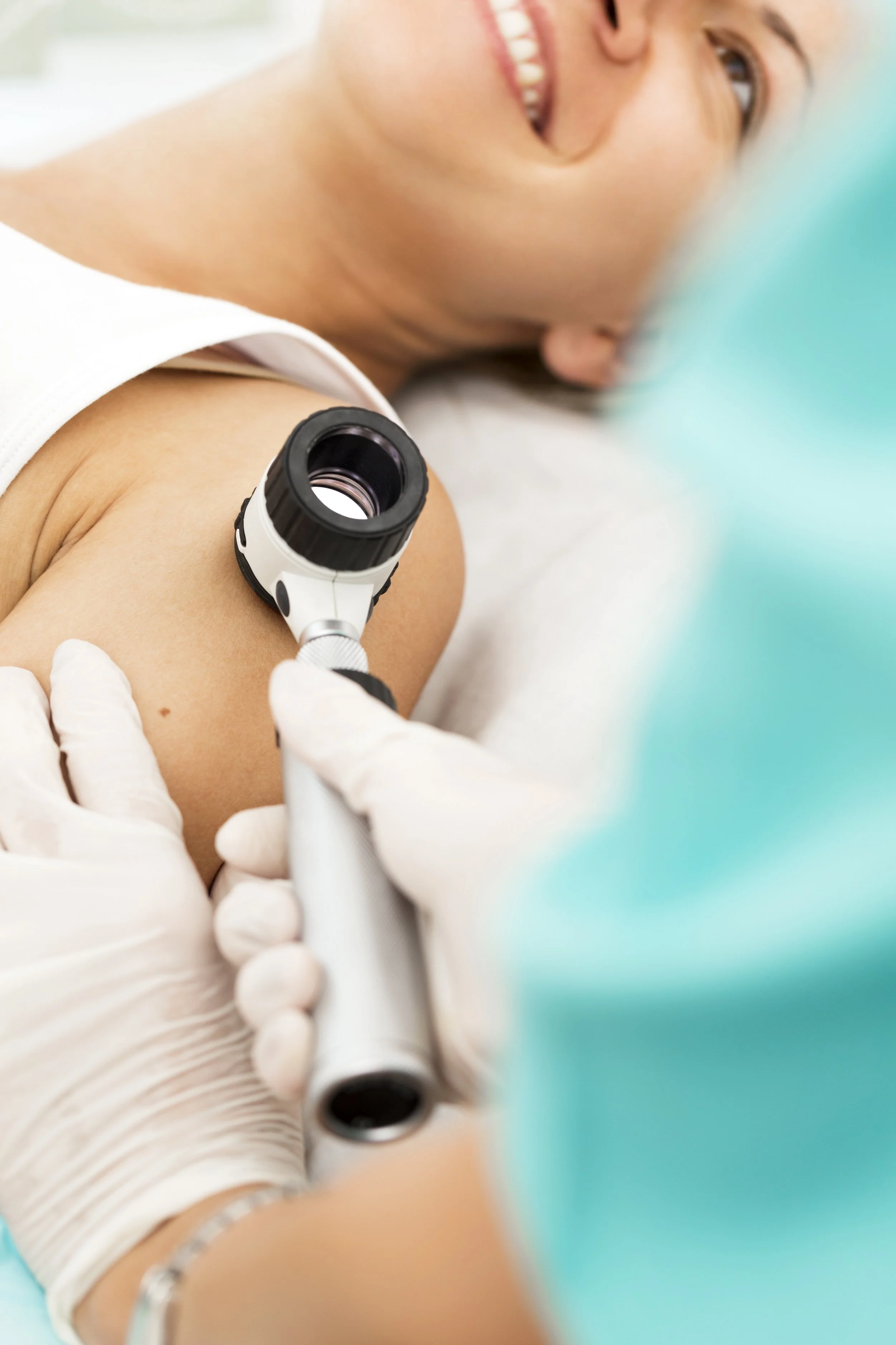Close-up of a person lying down and smiling while getting a vaccination in their upper arm, with a healthcare professional wearing gloves administering the shot.
