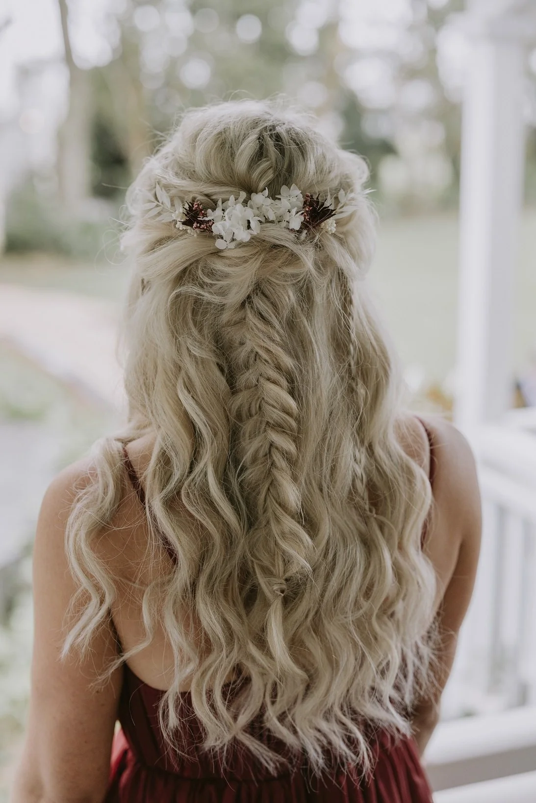 Woman with long, wavy blonde hair wearing a floral headband, seen from behind.