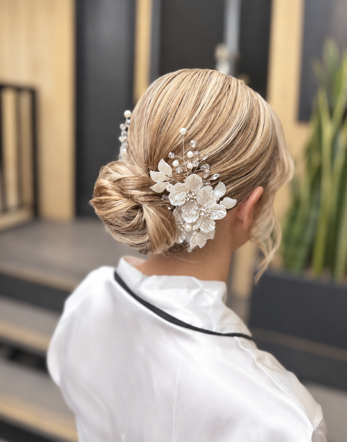 sleek blonde low bun with white floral hair accessory