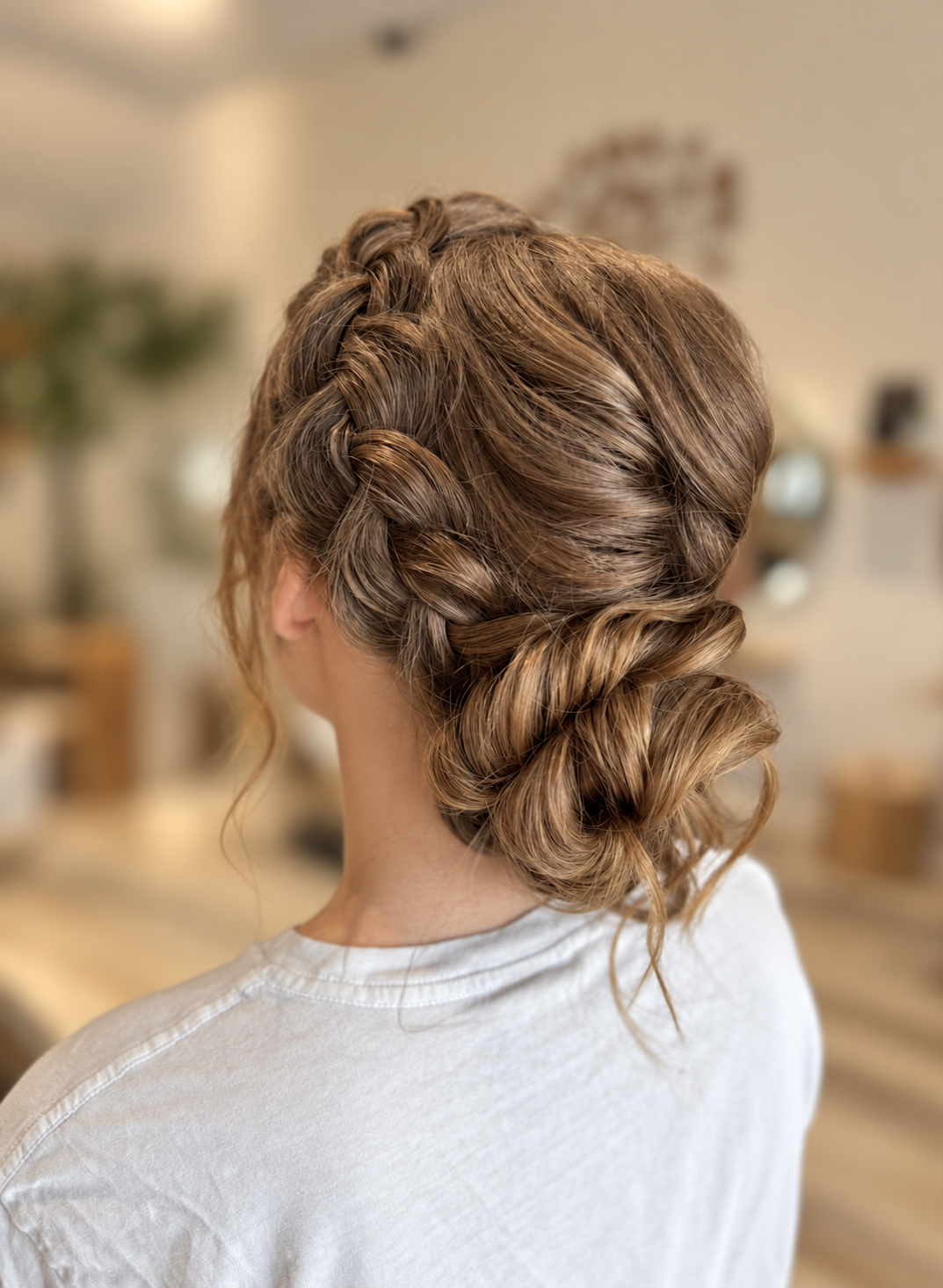 low textured bun on light brown hair and highlighted for dimension, side braid