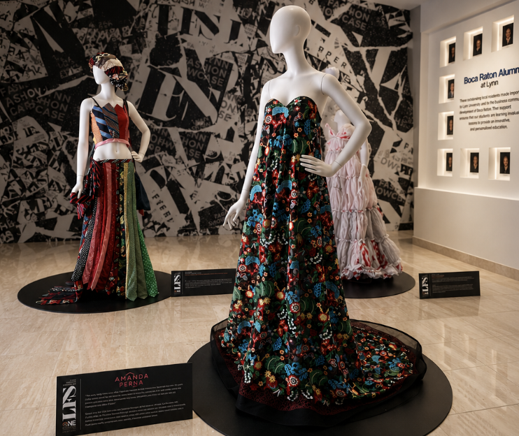 Exhibit of mannequins wearing colorful, traditional and modern dresses at Boca Raton Museum of Art, with informational plaques and a black-and-white collage wall background.