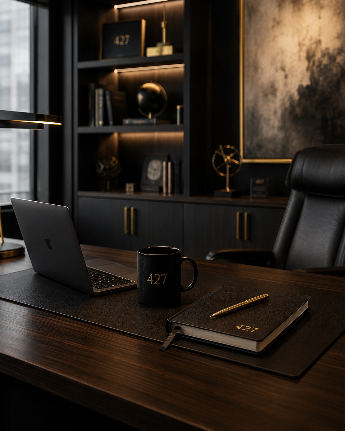 Office desk with a laptop, black coffee mug, and a notebook with a gold pen, in a modern dark wood office with black shelving and decorative items.