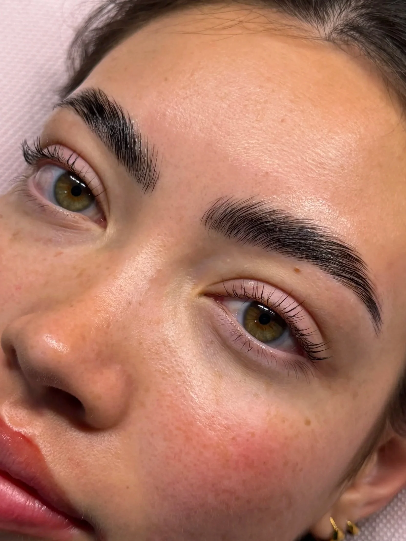 Close-up of a woman's face focusing on her brown eyes and eyebrows, with well-groomed eyebrows and natural makeup.