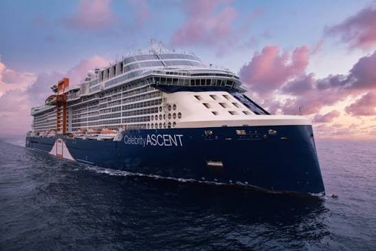 Large cruise ship named Celebrity Ascent sailing on the ocean during sunset.