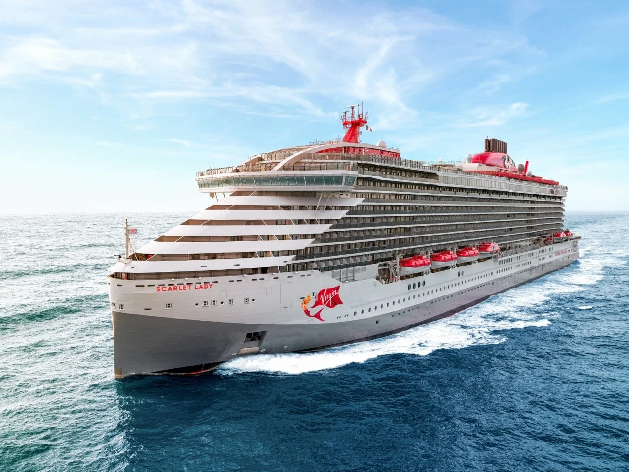 Large cruise ship named Scarlet Lady sailing on the ocean with clear blue skies.
