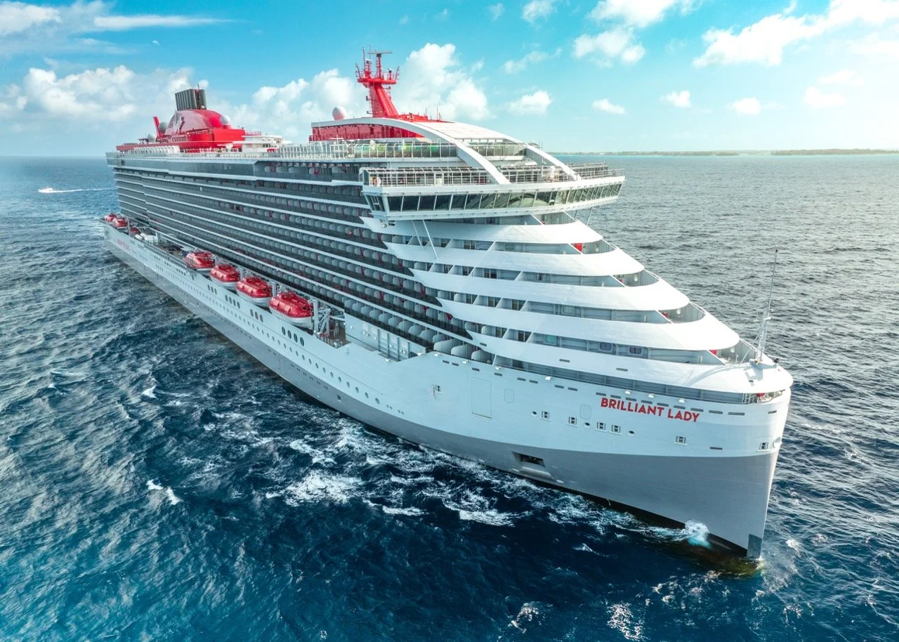 Large white cruise ship named 'Brilliant Lady' sailing on the ocean with a partly cloudy sky in the background.