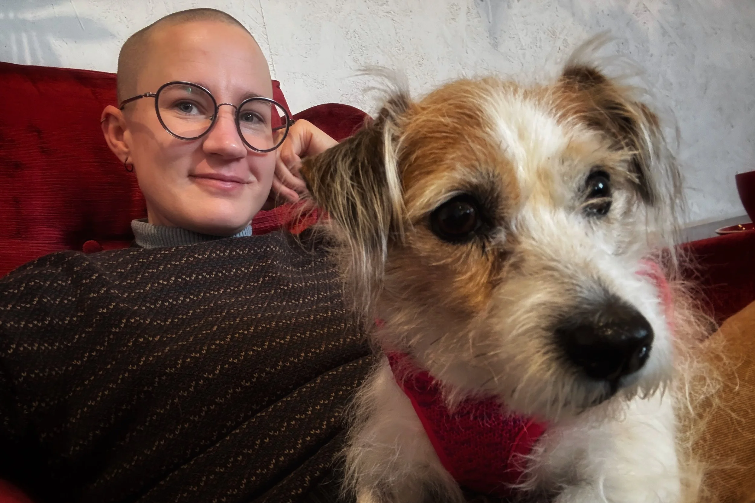 Fremantle artist Hannah smiling with her dog, Sashie, while sitting together on a red couch.