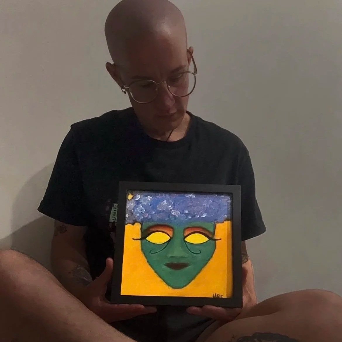 Artist Hannah holding one of her original framed paintings.