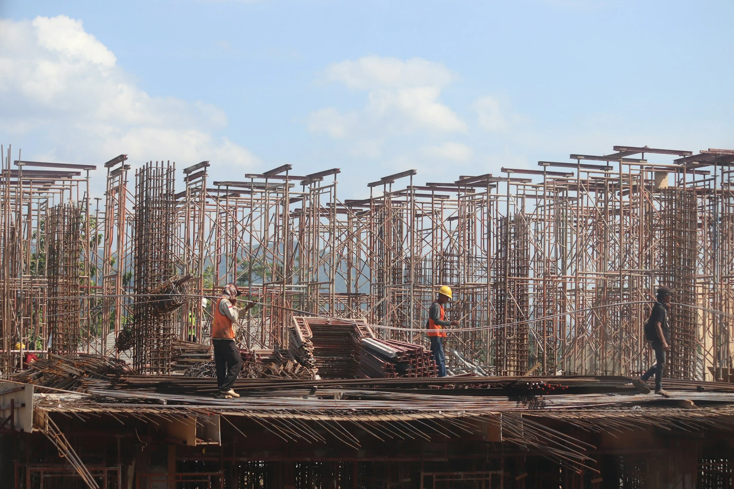 Construction site with steel scaffolding and workers wearing helmets.