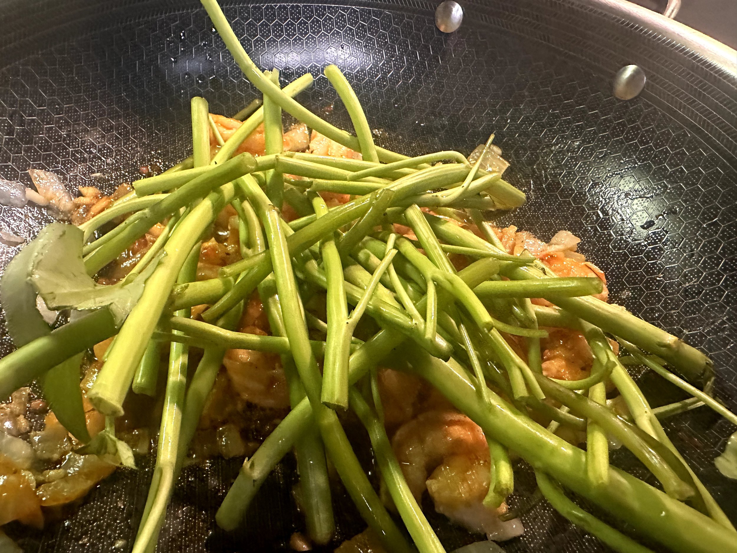 Kangkung stalks cooking with shrimp, tomatoes and belachan sauce