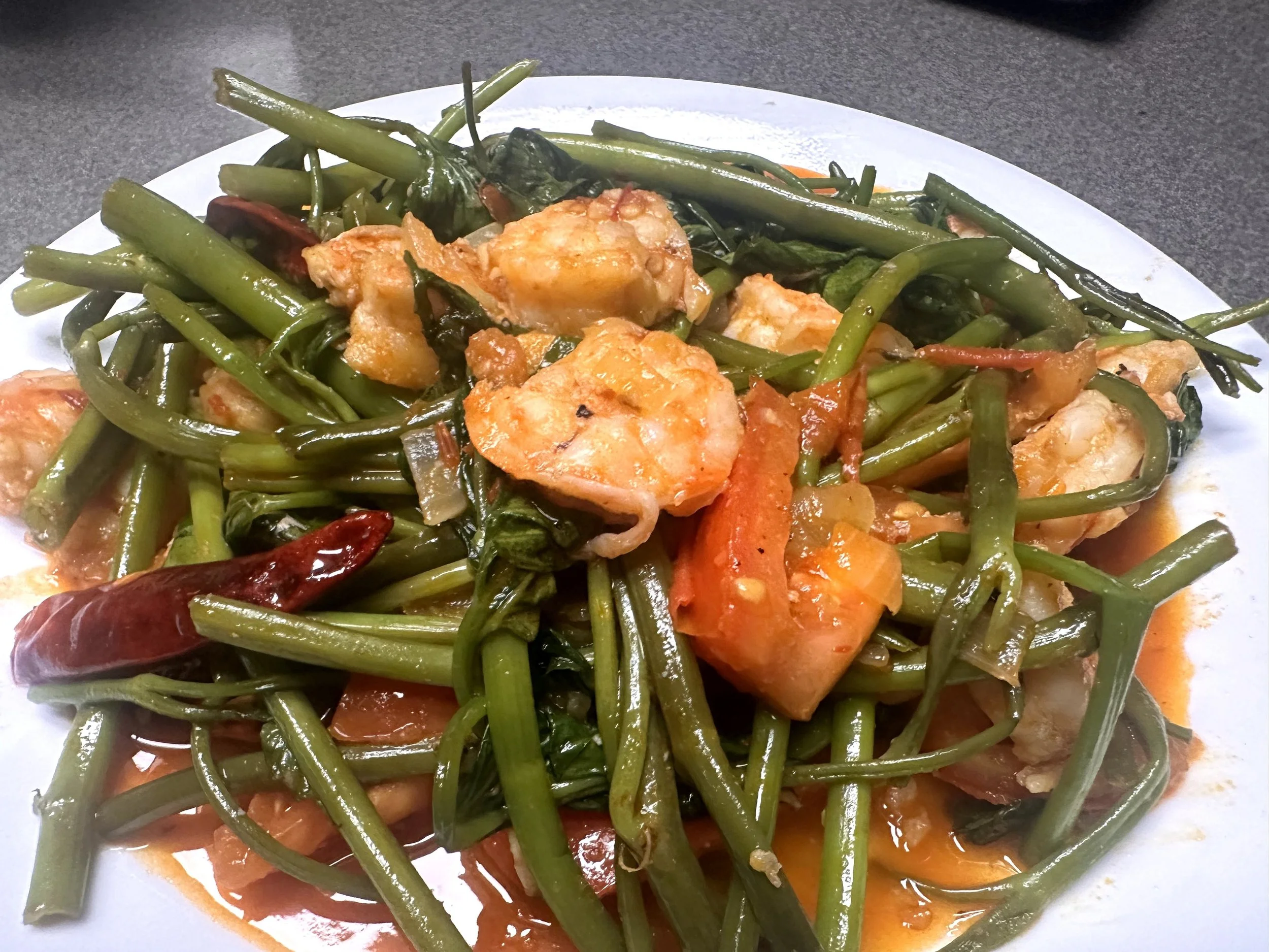 Finished homemade kangkung belachan with shrimp, tomatoes and dried chili