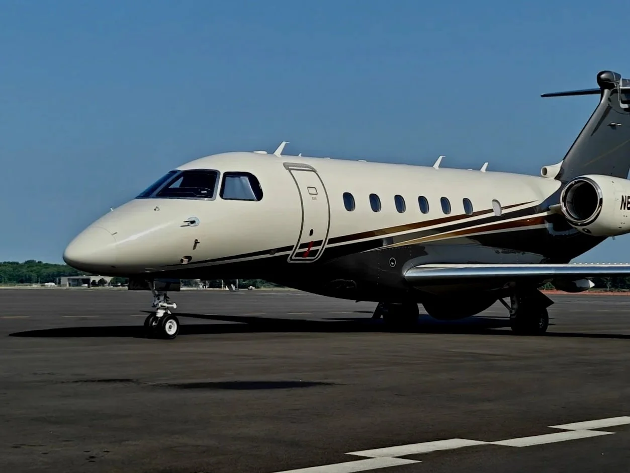 Private jet on airport tarmac with blue sky in background.