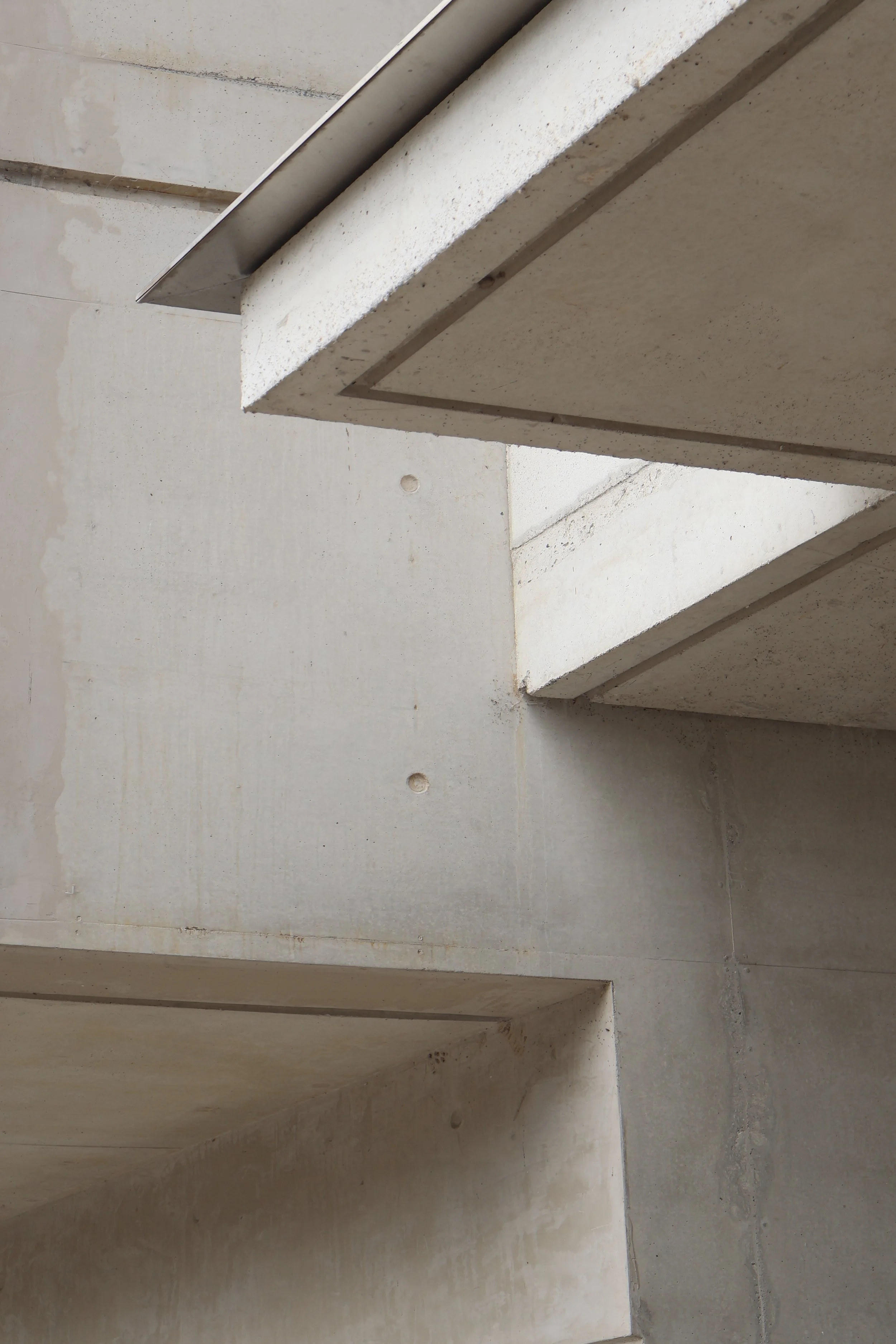 Close-up of an architectural detail showing concrete stairs with visible lines and textures, viewed from below.