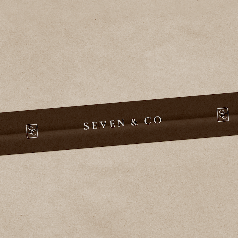 A beige box with a brown band reading 'SEVEN & CO' and small square logos on each end.