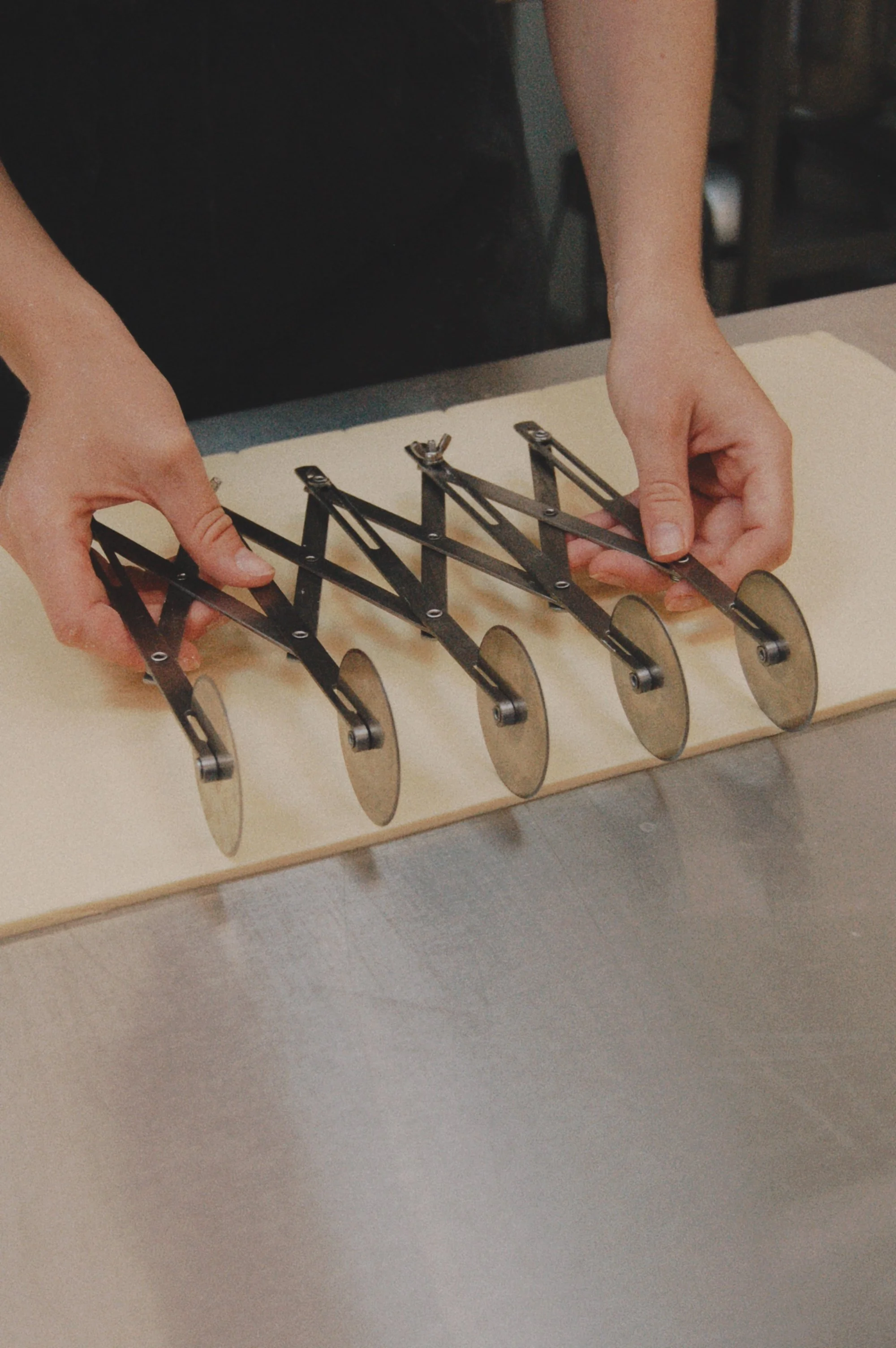 A person assembling a mechanical clock with metal gears and arms on a table.