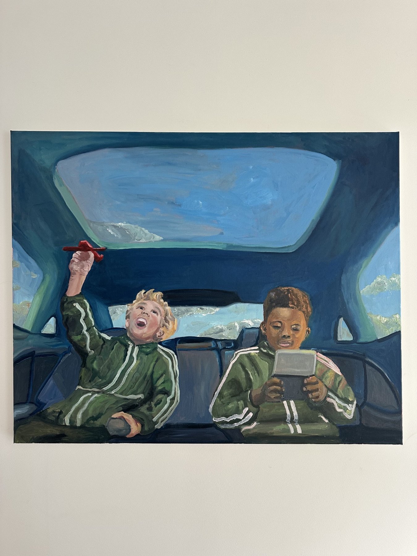 To børn i en bil, et virker som om de leger og har det sjovt, den ene er opslugt af en tablet, den anden laver en håndbevægelse.